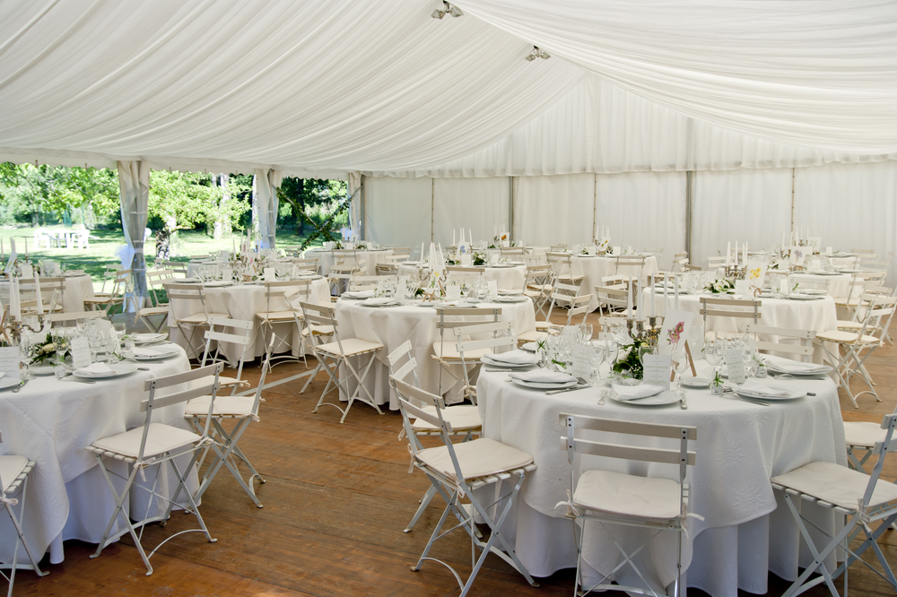 tables and chairs arranged under a tent for a wedding reception outdoors