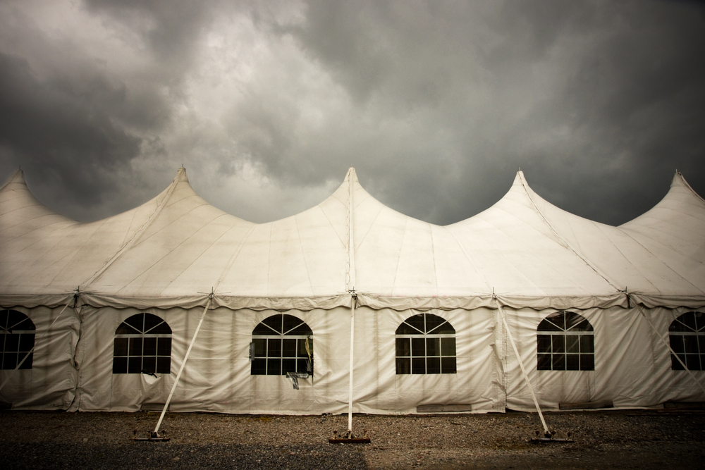 dark clouds forming above a white outdoor event tent