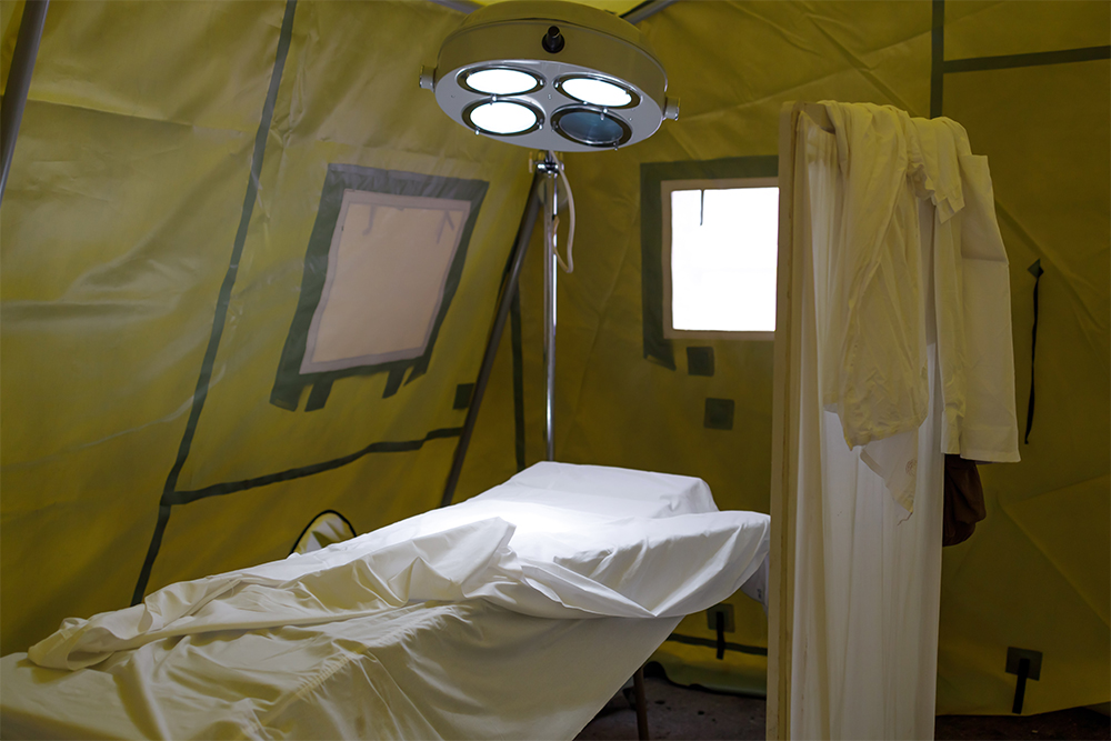 A makeshift doctors' bed set up in a military tent.