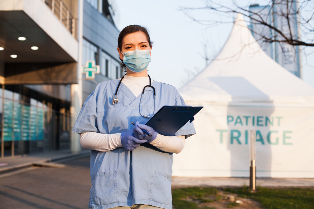 a doctor in scrubs standing in front of a medical tent