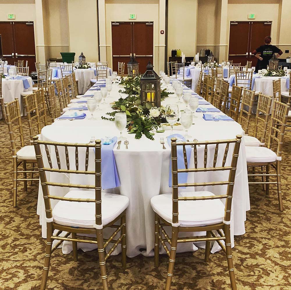 a hotel event room set up with rented tables, chairs, tablecloths, and decorations