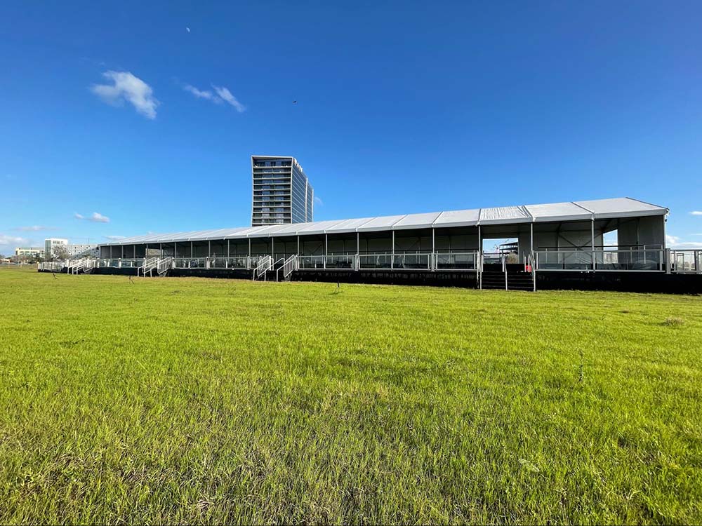 an outdoor event tent set up on the grass in front of the Lake Nona Wave Hotel