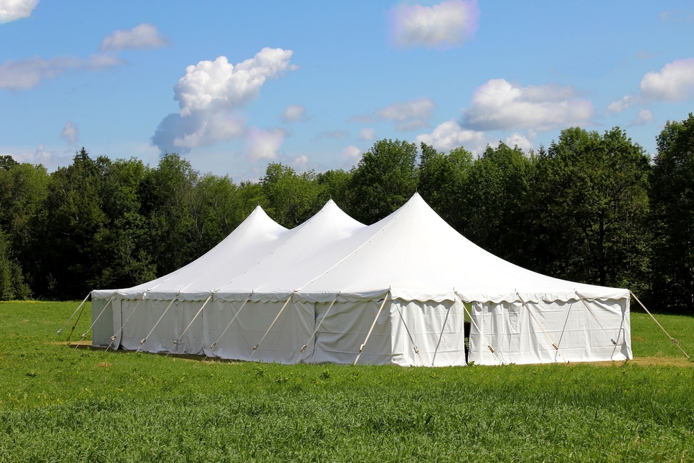 a white event tent in a field with sidewalls attached to it