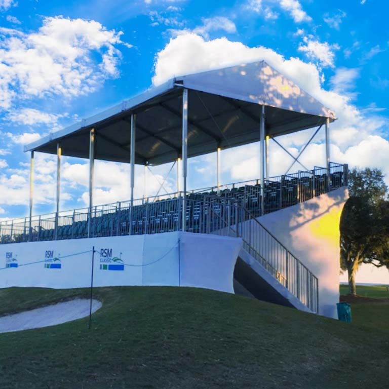 An outdoor tent on top of a section of bleachers for an outdoor concert