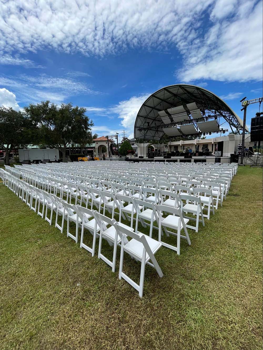 An outdoor stage with rows of white chairs lined out in front of it