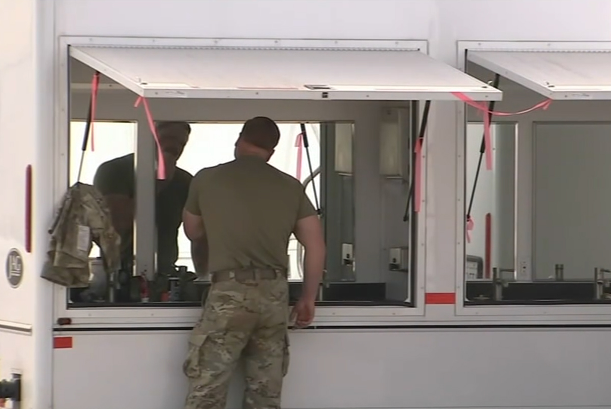 Soldier shaving face in front of sink trailer